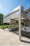 Pergola aluminium sur mesure bioclimatique à lames blanches sur terrasse bois avec vue sur lac et transats