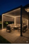 Pergola aluminium sur mesure gris anthracite avec éclairage LED intégré et salon extérieur de nuit ambiance chaleureuse
