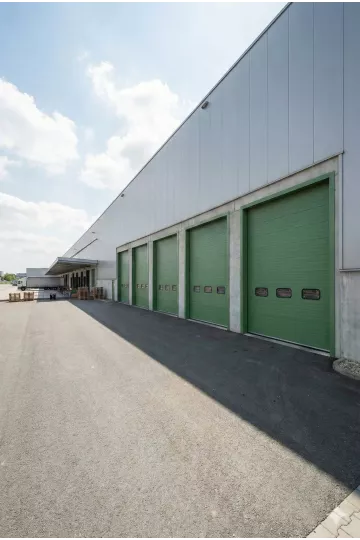 Portes sectionnelles industrielles vertes alignées hangar entrepôt bardage métallique hublots