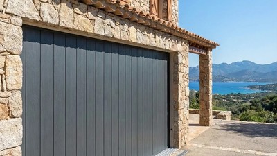 Porte de garage coulissante latérale motorisée grise sur maison en pierre en Corse