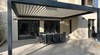 Pergola bioclimatique adossée à une maison moderne - baies vitrées et salon de terrasse