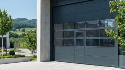 Porte sectionnelle avec portillon intégré et panneaux vitrés – accès piéton indépendant sur bâtiment