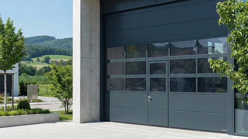 Porte sectionnelle avec portillon intégré et panneaux vitrés – accès piéton indépendant sur bâtiment