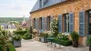 Volets battants PVC persiennés bleu-gris sur une maison en brique et pierre en Île-de-France, jardin fleuri