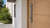 Poignée de tirage inox posée sur une porte d'entrée en bois